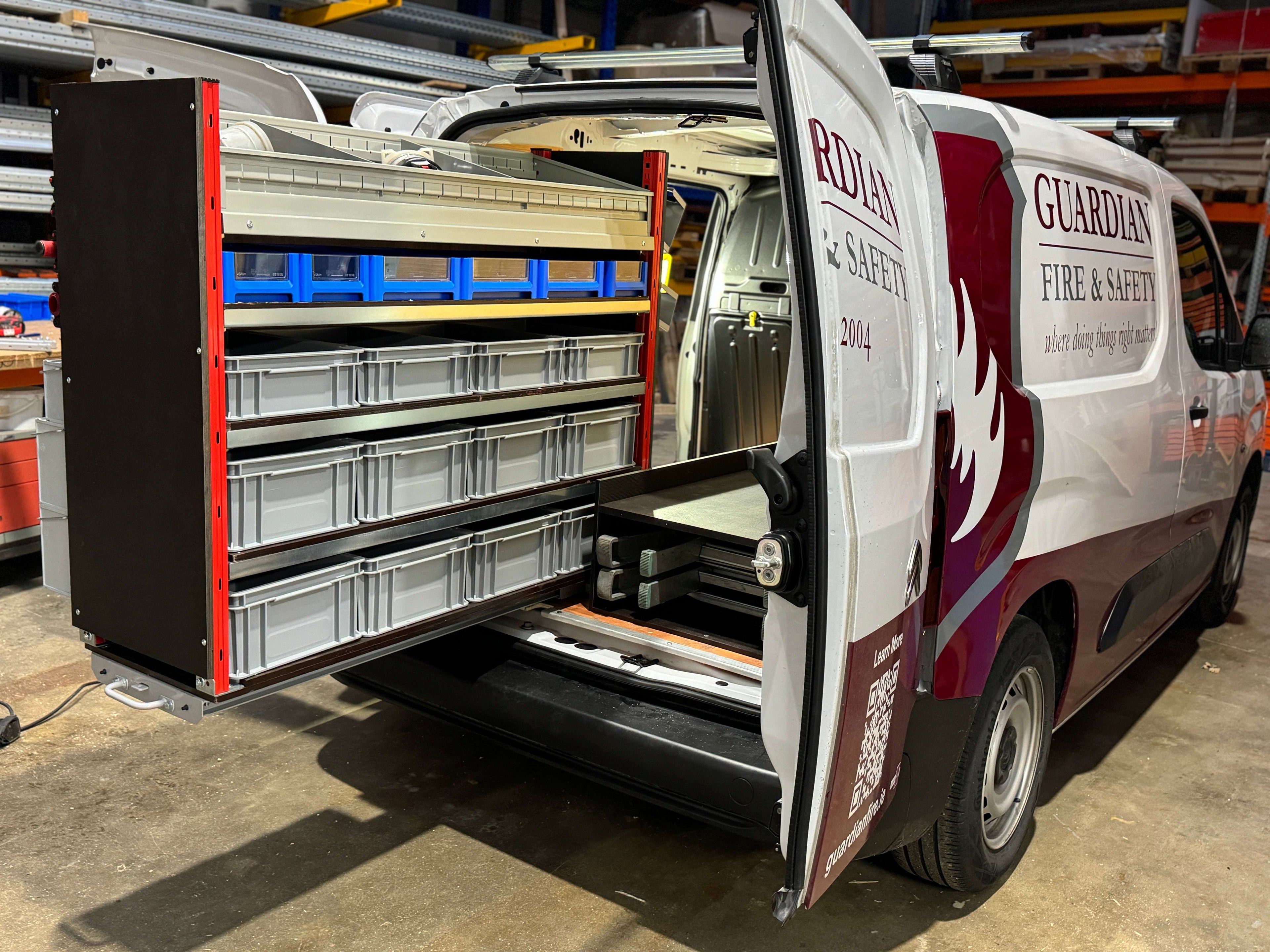 A Picture of a Pull Out Shelving Unit in a Van with Selections of Grey Euro Boxes and Blue Shelf Bins with a Bin Kit