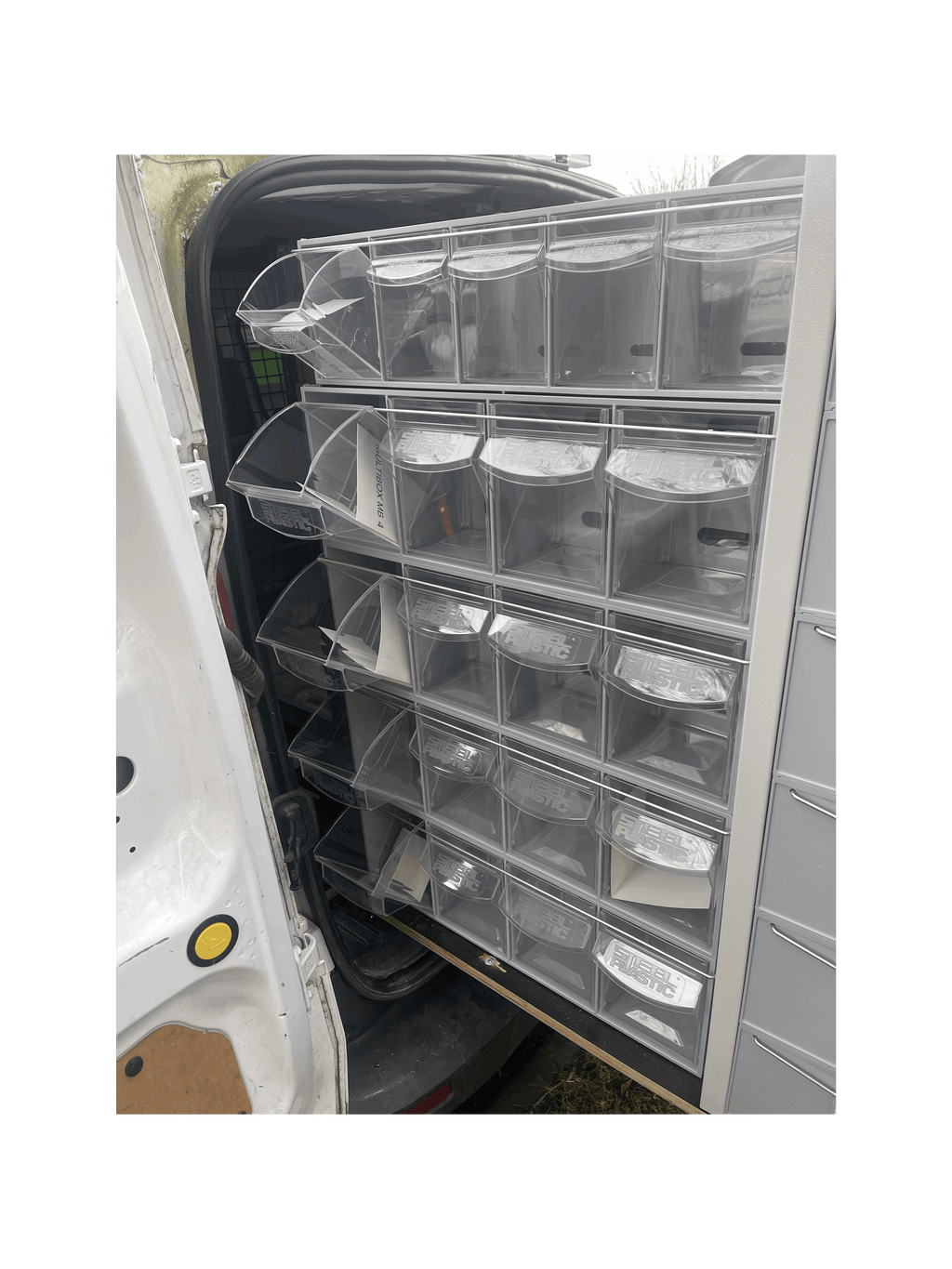 A Stack of MB Boxes on the Back of a Pull Out Shelving Unit in a Van