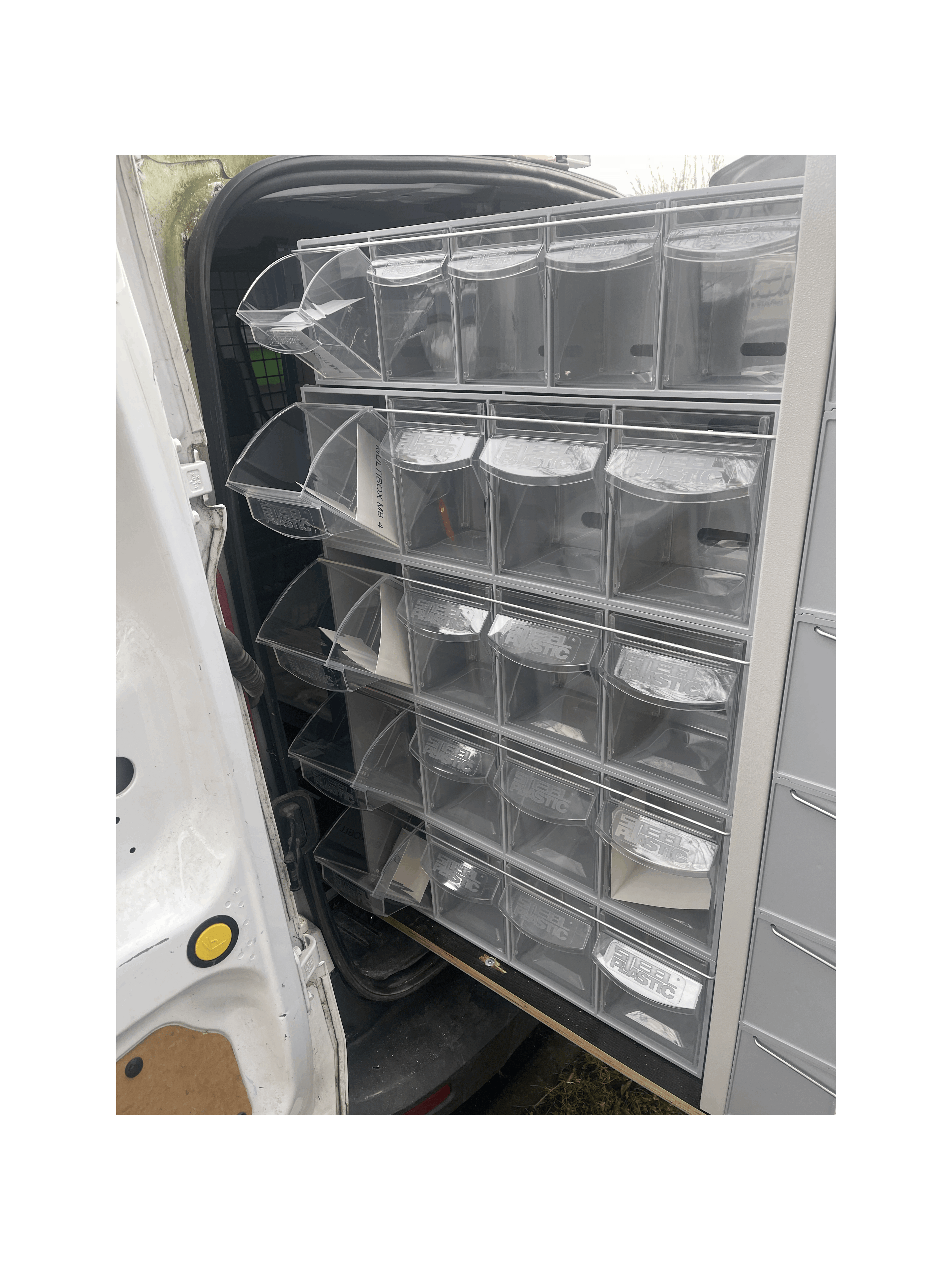A Stack of MB Boxes on the Back of a Pull Out Shelving Unit in a Van