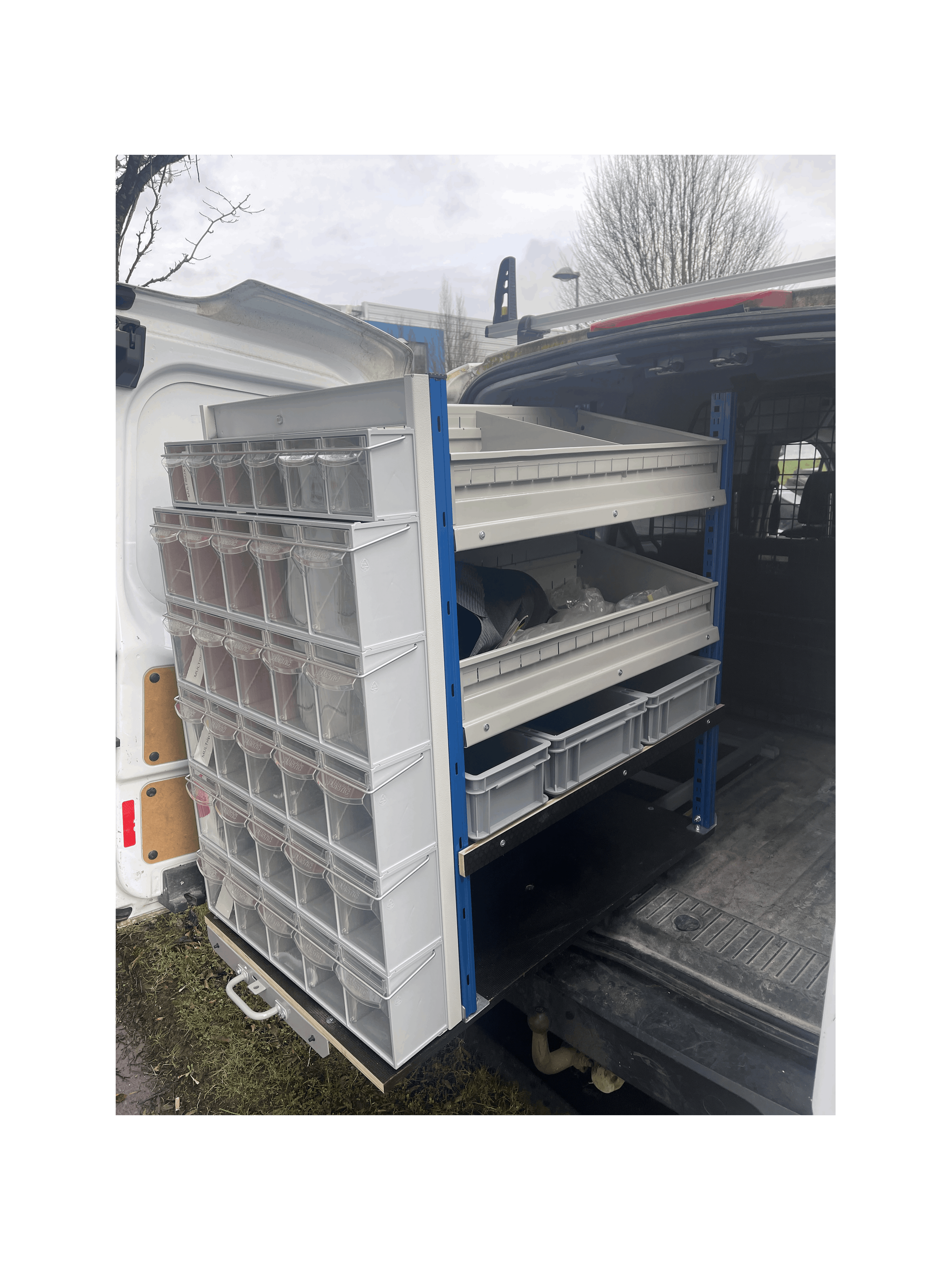 A Stack of MB Boxes on the Back of a Pull Out Shelving Unit with a Selection of Grey Euro Boxes and 2 Bin Kits in a Van