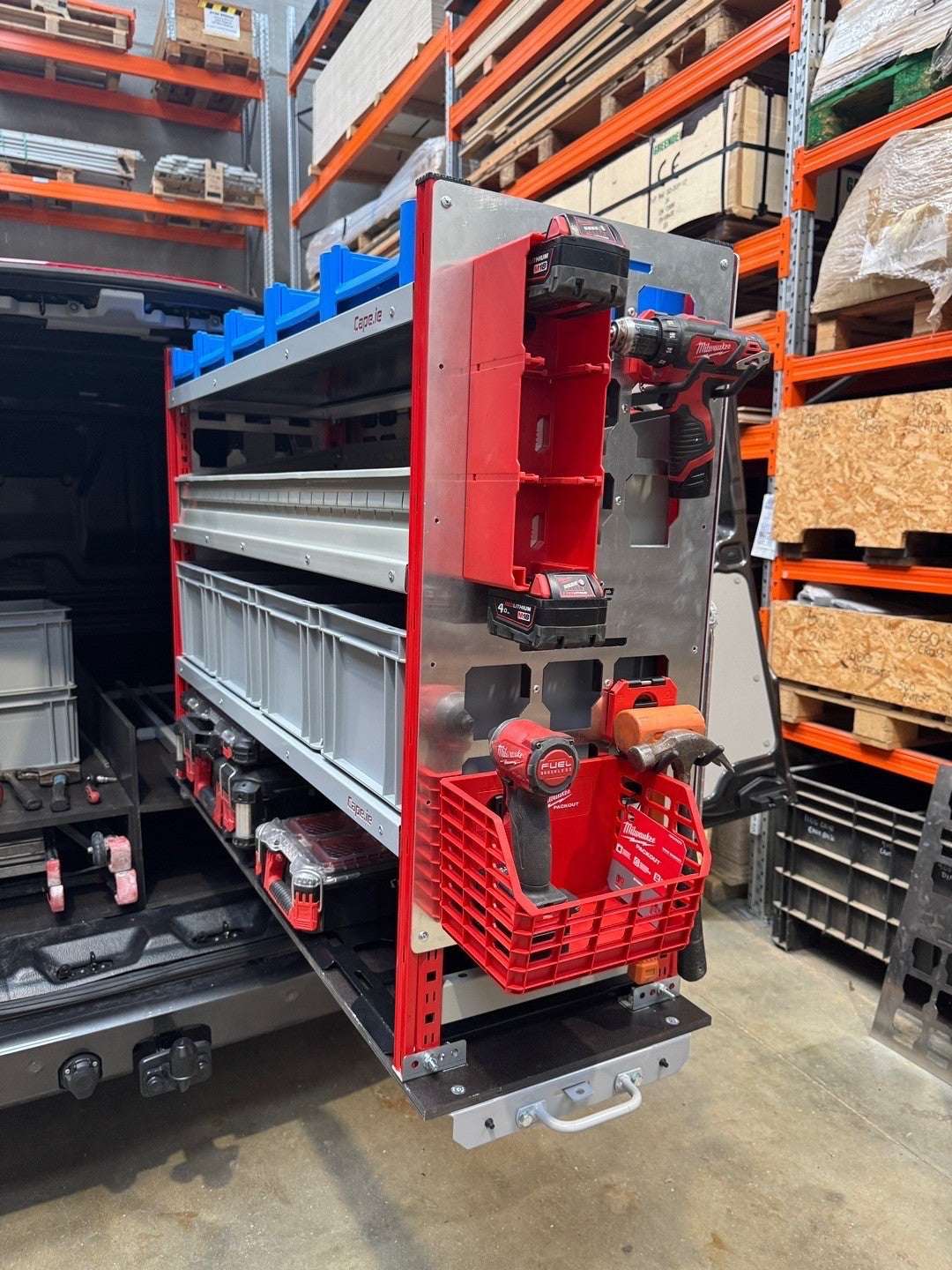 Picture of a Milwaukee Packout Pull Out Shelving Unit in a Van with Selections of Blue Shelf Bins and Grey Euro Boxes, a Bin Kit, Milwaukee Packout Shelf Plates with Milwaukee Packout Accessories Clipped onto the Milwaukee Packout Gable.