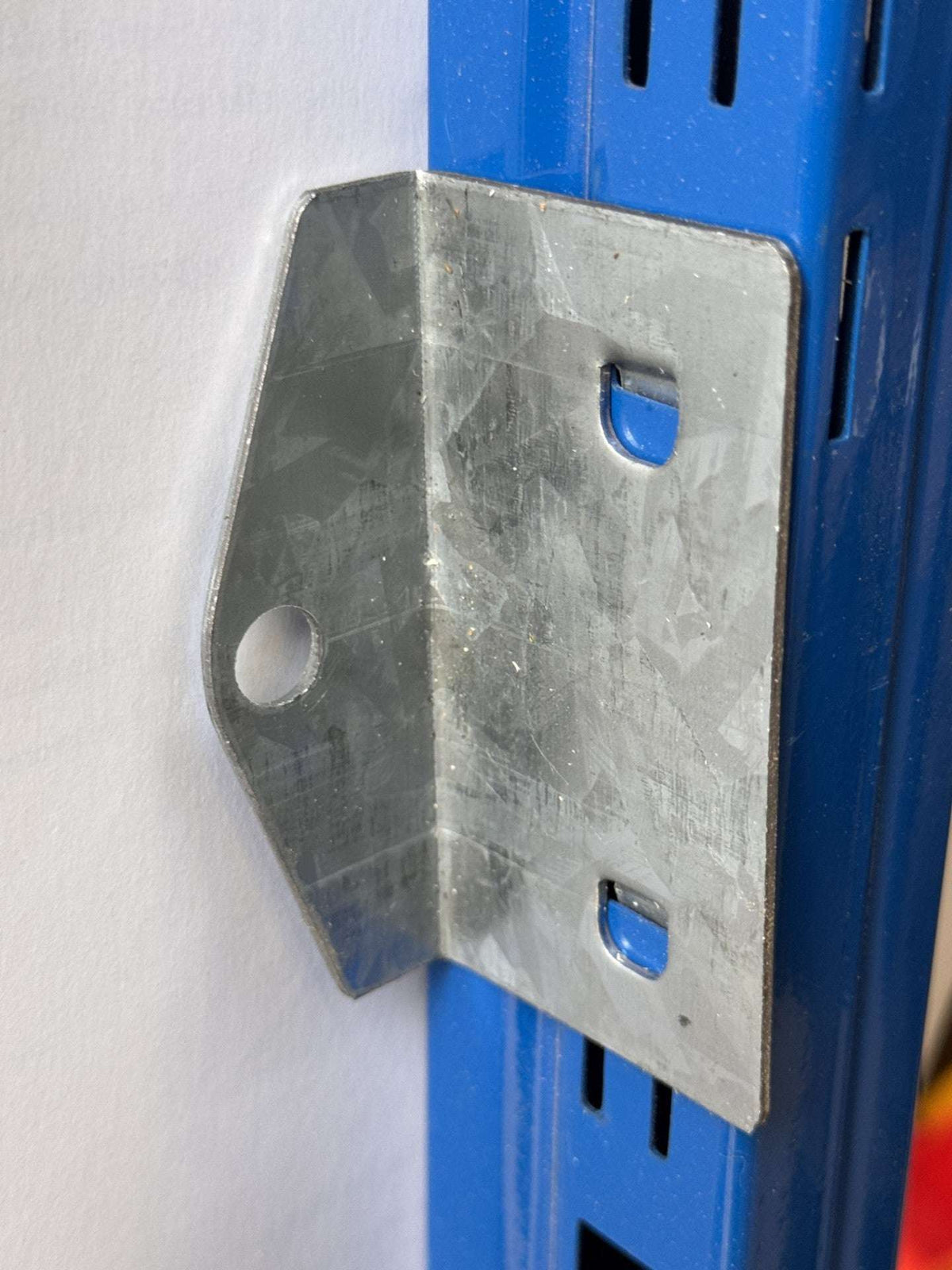 Image of a ST30 Wall Clamp Clipped onto a Blue ST30 Upright pressed against a Wall